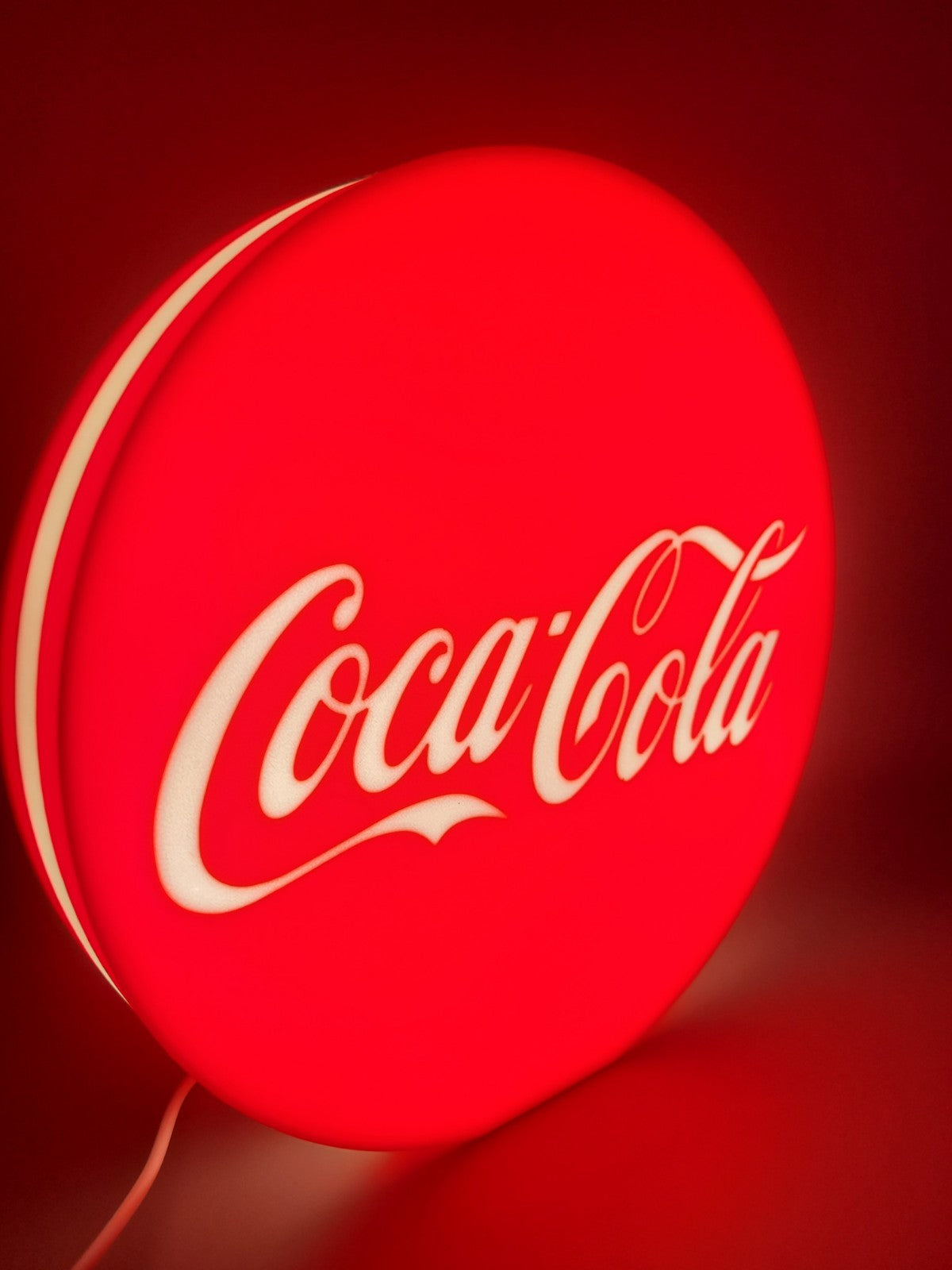 Coca-cola LED light sign with illuminated logo viewed from side view