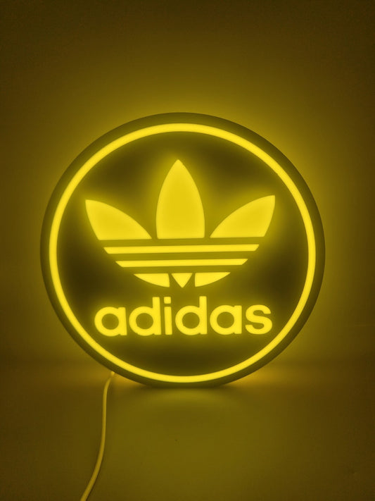 Adidas yellow LED light sign with illuminated logo viewed from straight on