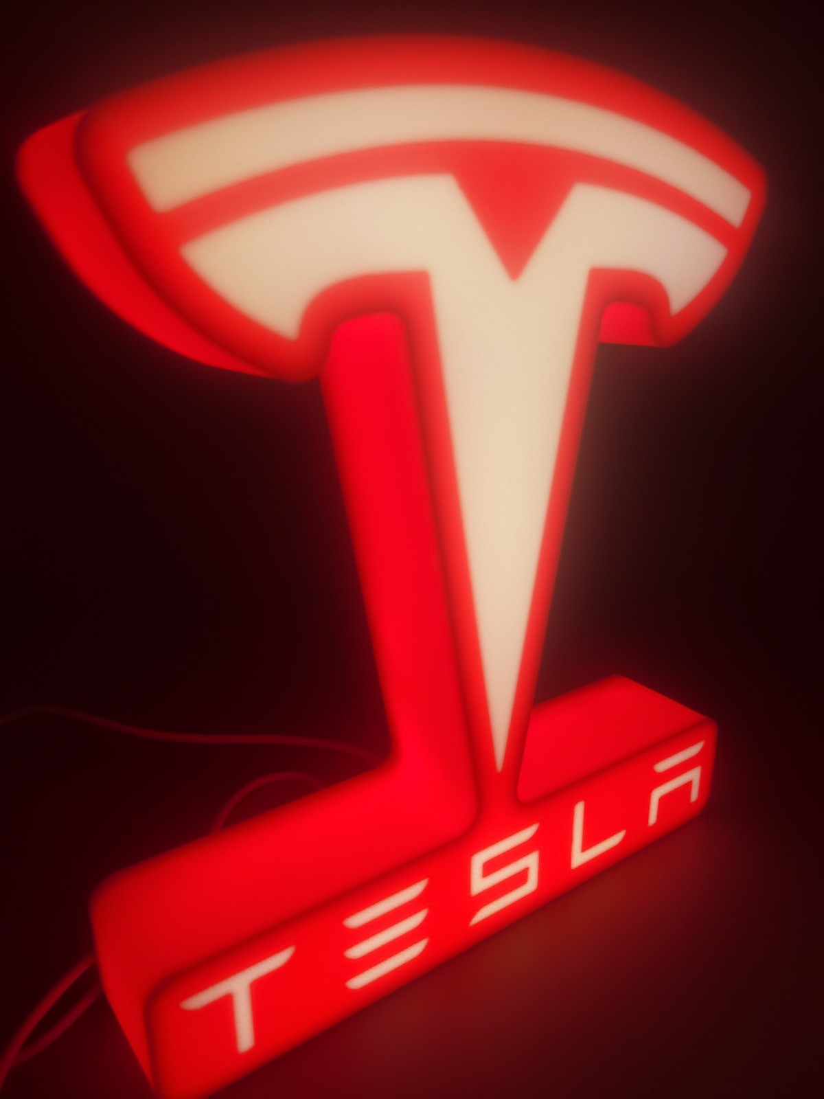 tesla LED light sign with illuminated logo viewed from side view