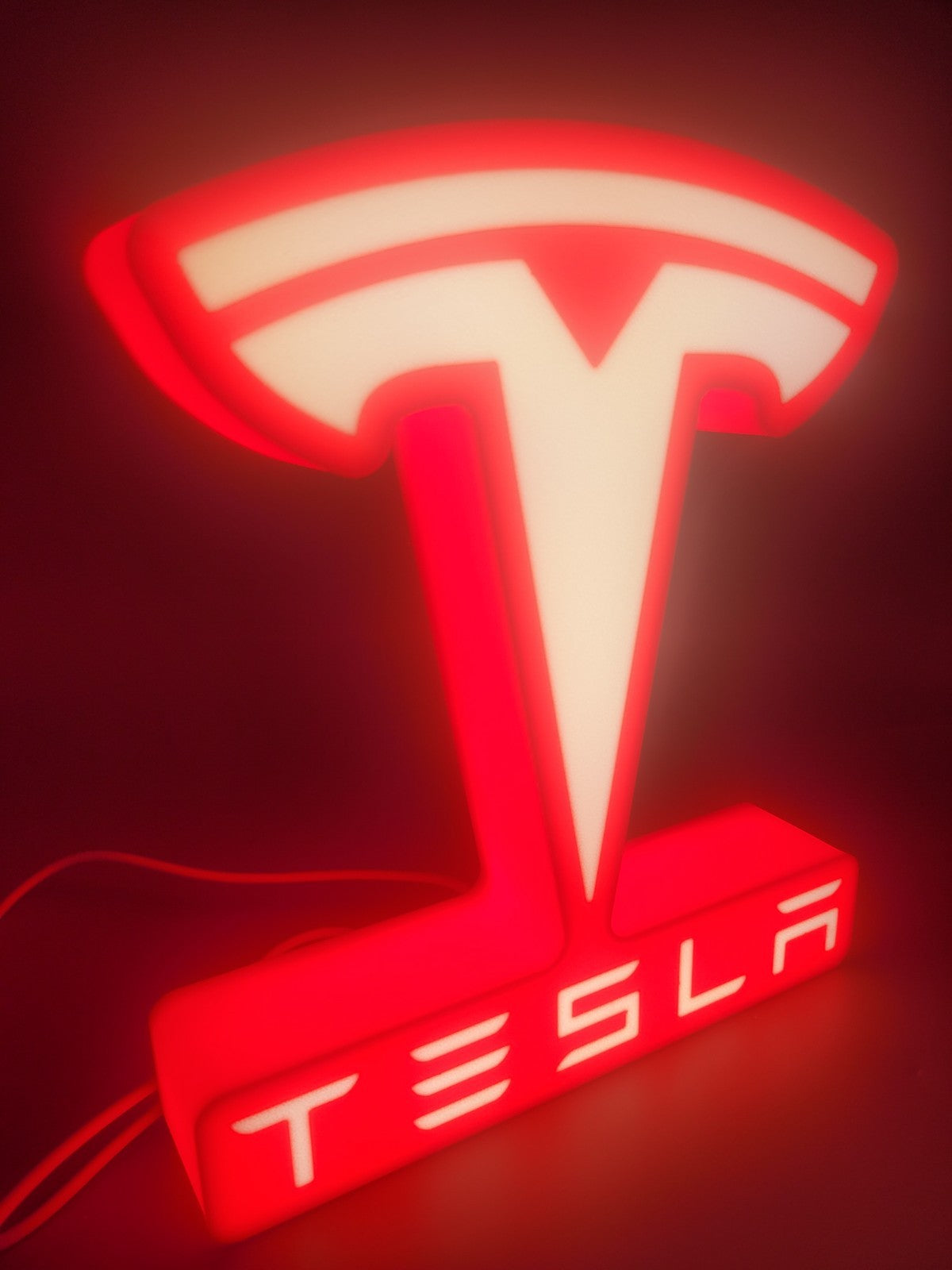 tesla LED light sign with illuminated logo viewed from side view
