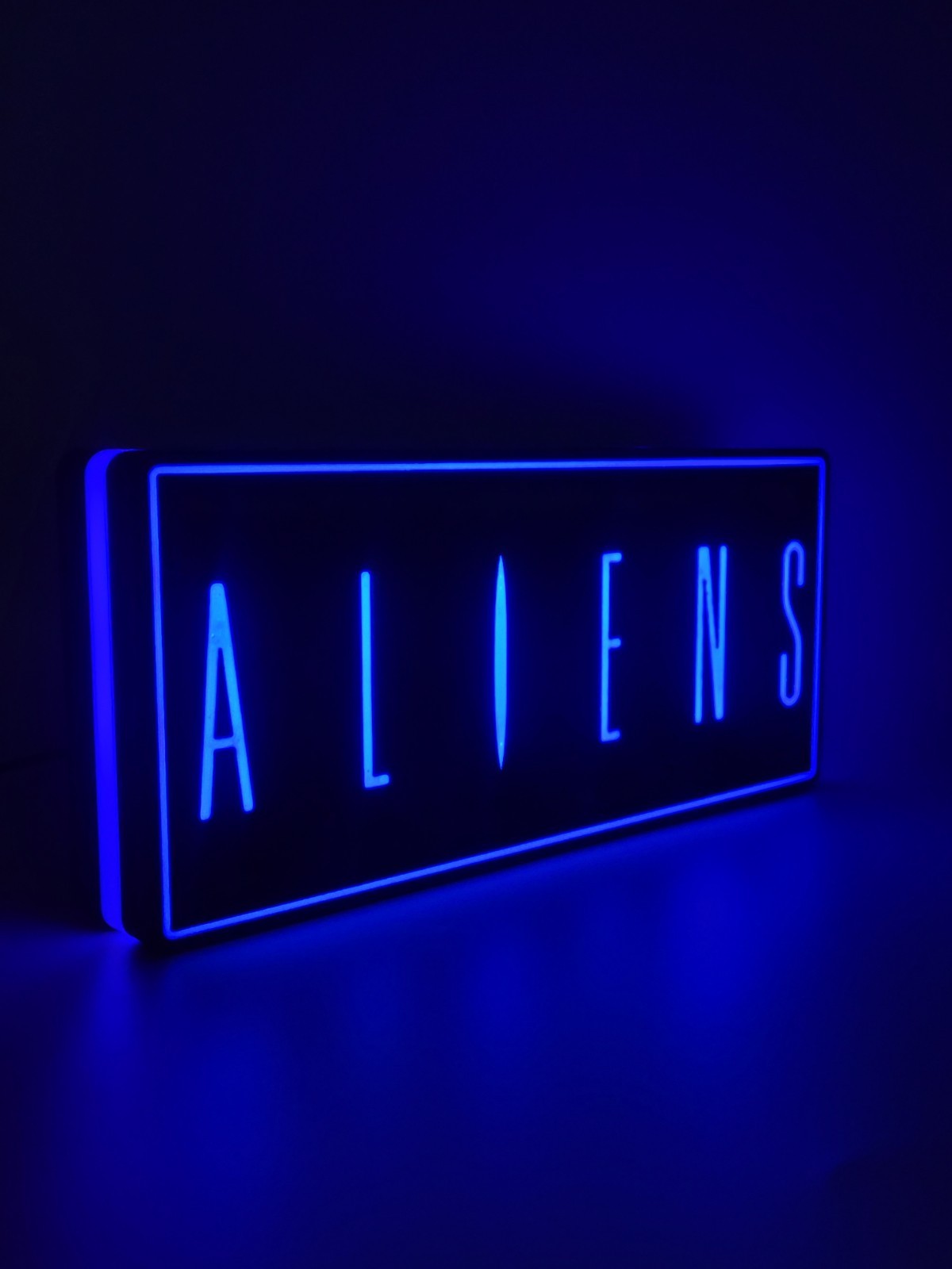 Aliens led light sign with illuminated logo viewed from side view
