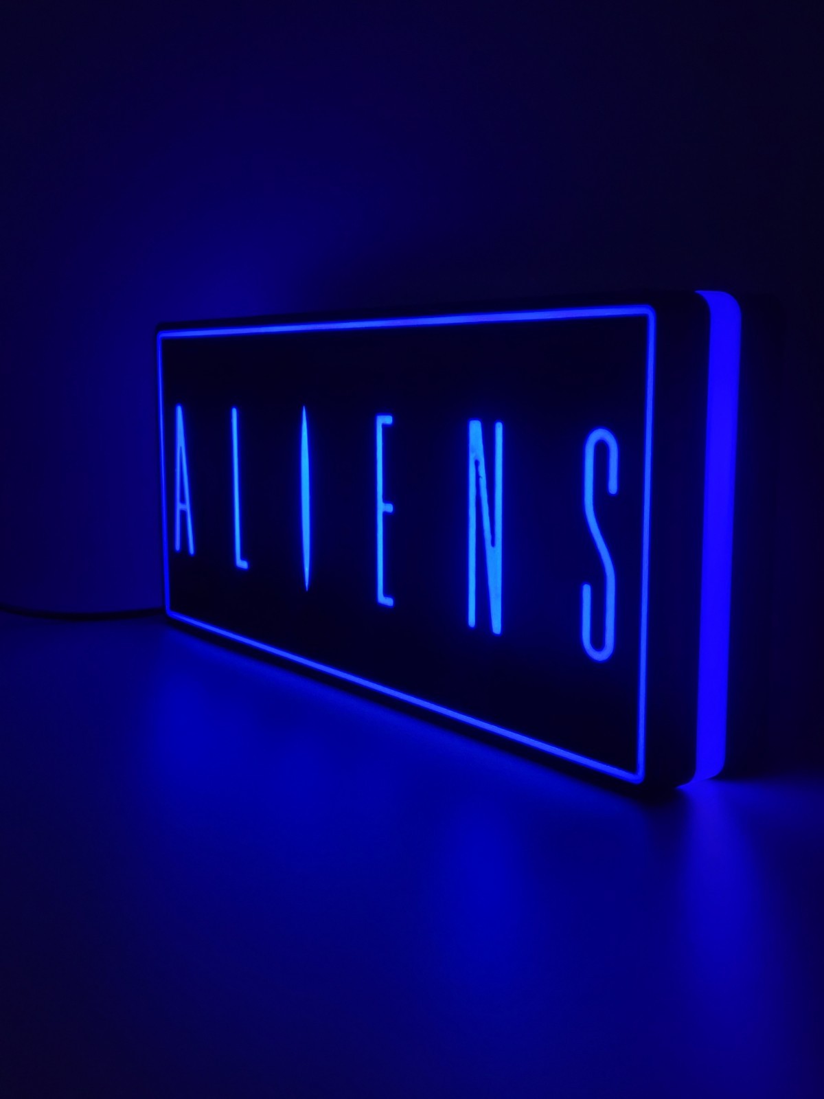 Aliens led light sign with illuminated logo viewed from side view