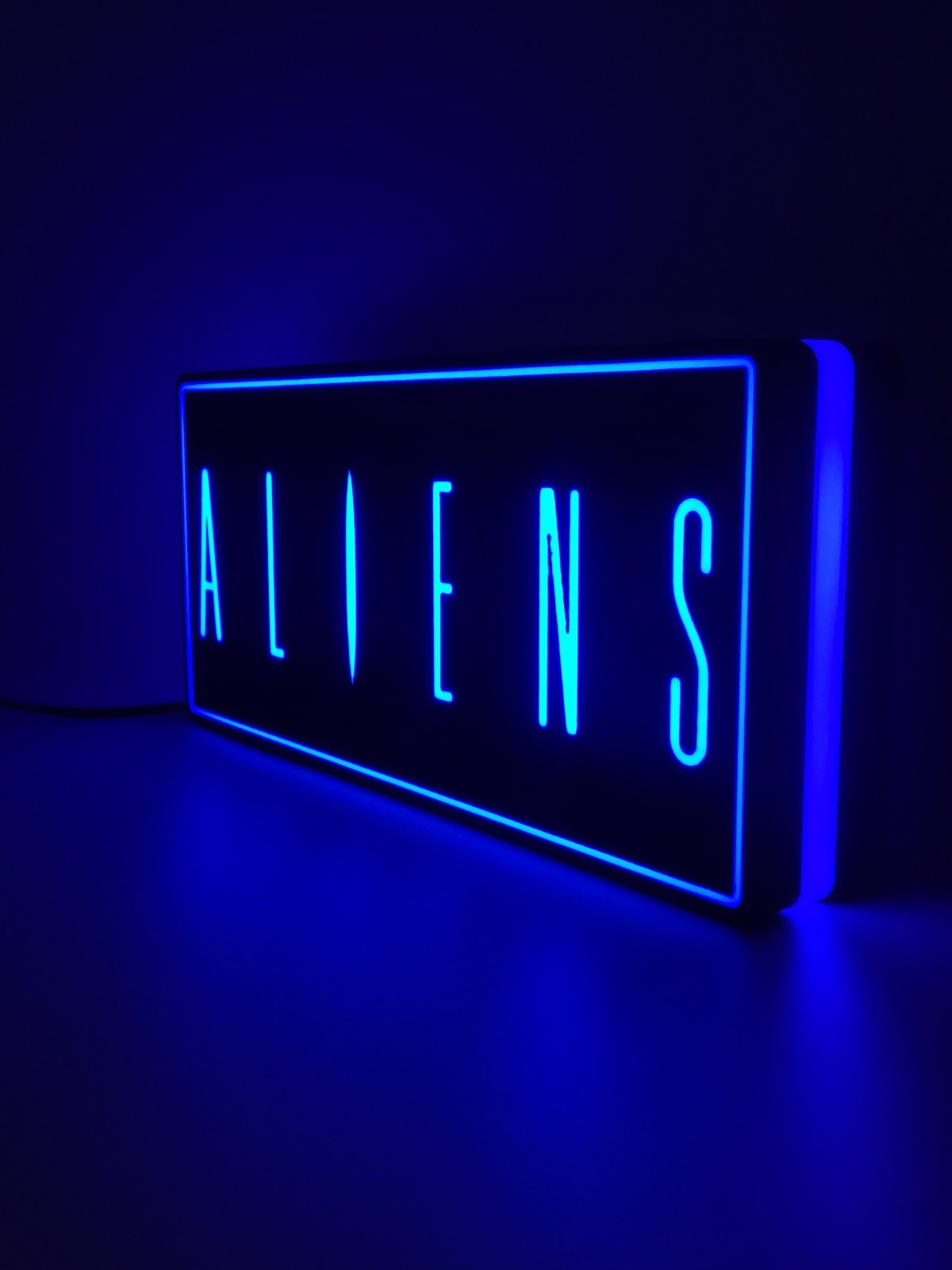 Aliens led light sign with illuminated logo viewed from side view