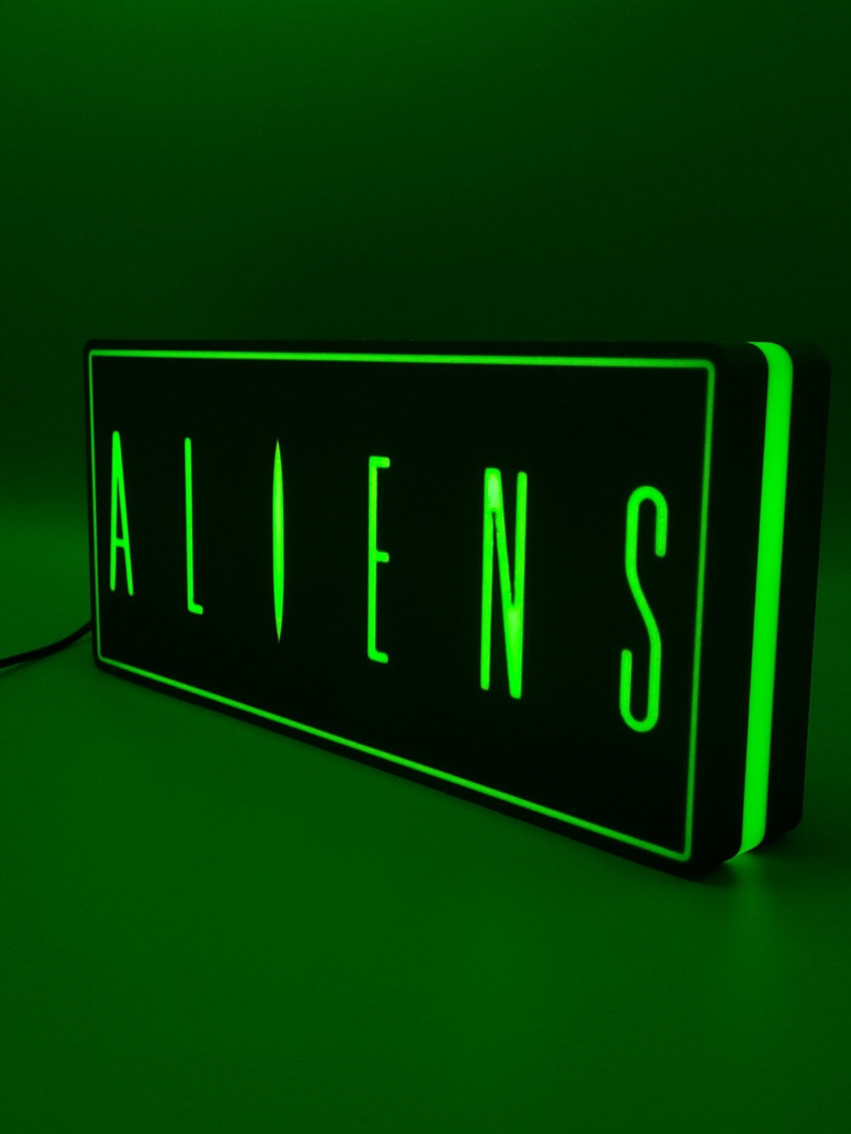 Aliens led light sign with illuminated logo viewed from side view