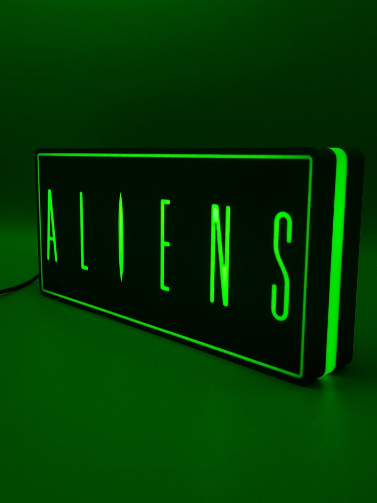 Aliens led light sign with illuminated logo viewed from side view
